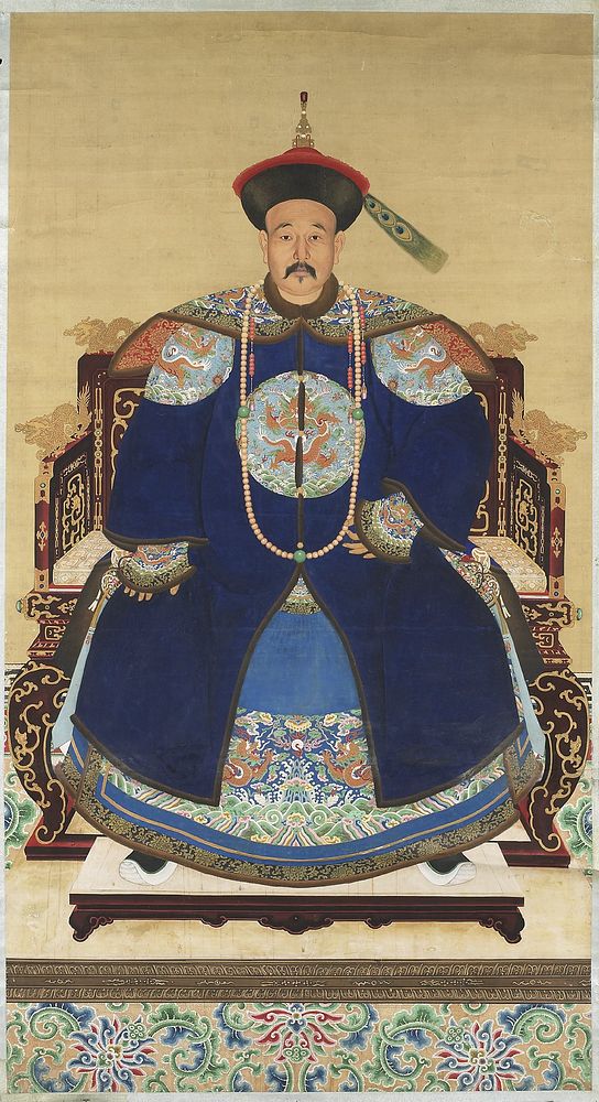 Seated man with a mustache wearing an elaborate blue robe and a red and black hat with a peacock feather; reddish-brown…