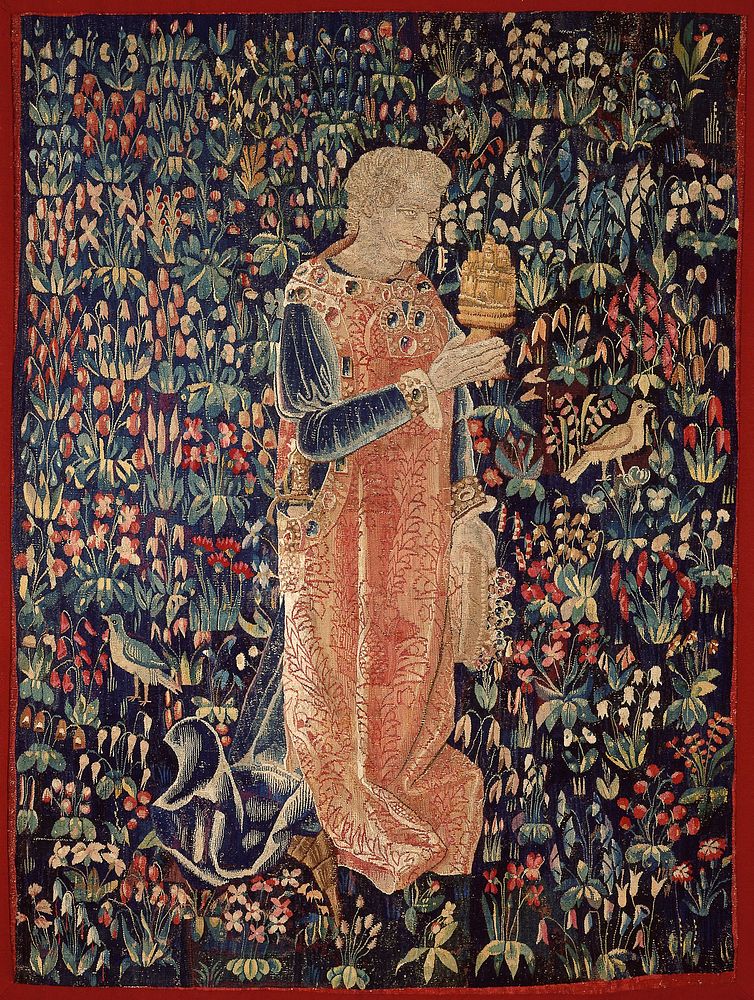 Tapestry. On a mille-fleur ground a knight wearing a sword and a surcoat, probably of velvet, with a design of large…