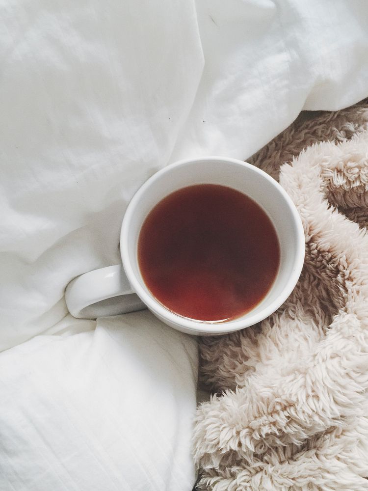 Free coffee in cozy bed, aesthetic photo, public domain beverage CC0 image.