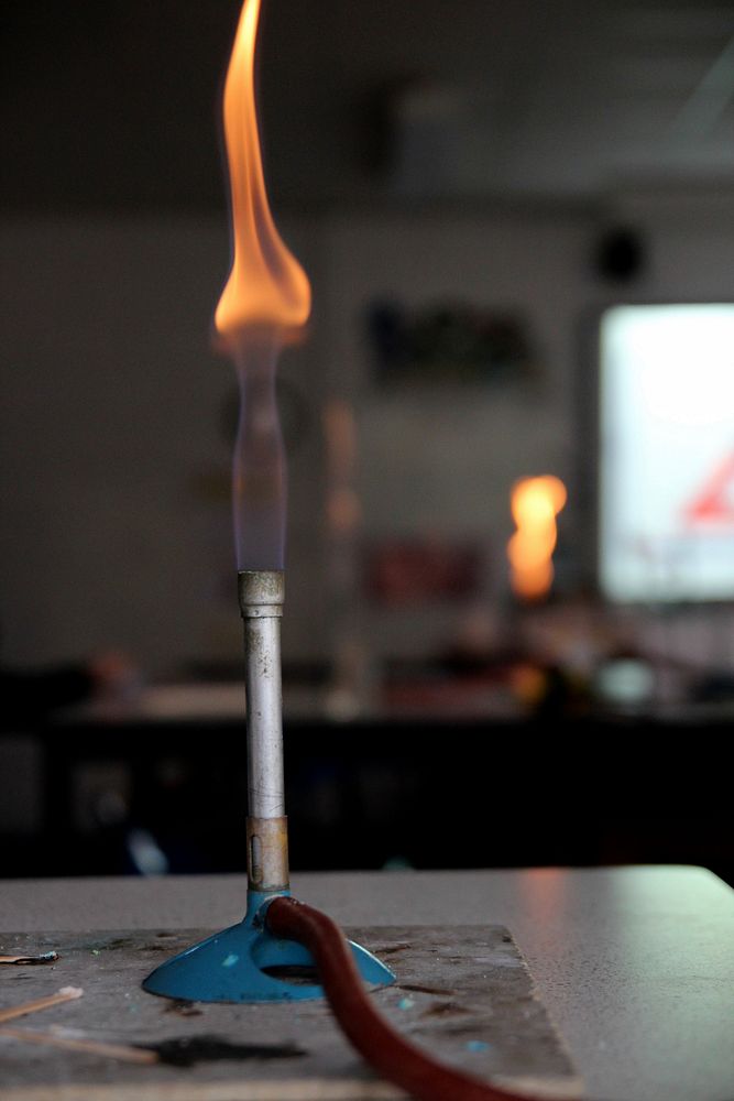 Gas burner with safety flame in school lab. Free public domain CC0 photo.