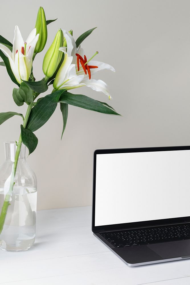 Aesthetic workspace with blank laptop screen and flower in vase