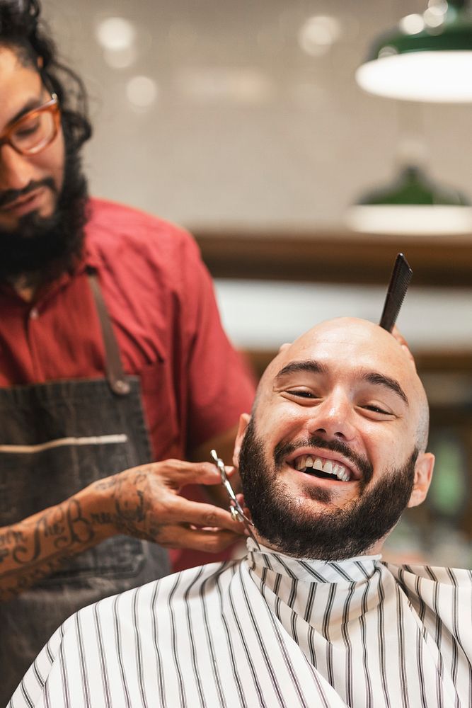 Barber trimming a customer's beard at a barber shop, small business