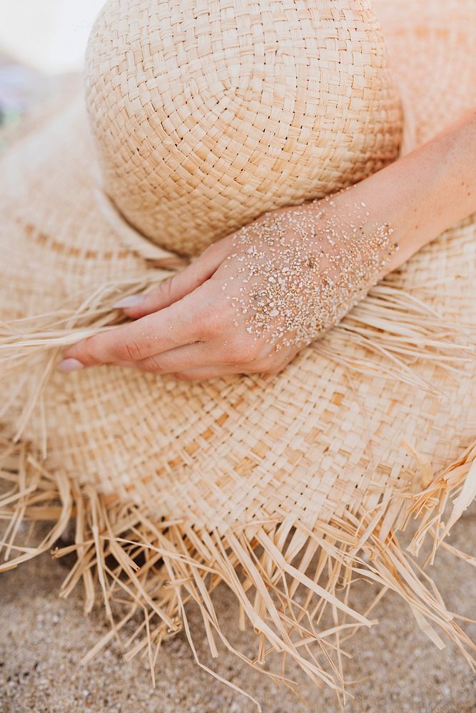 Sandy hand touch a straw hat