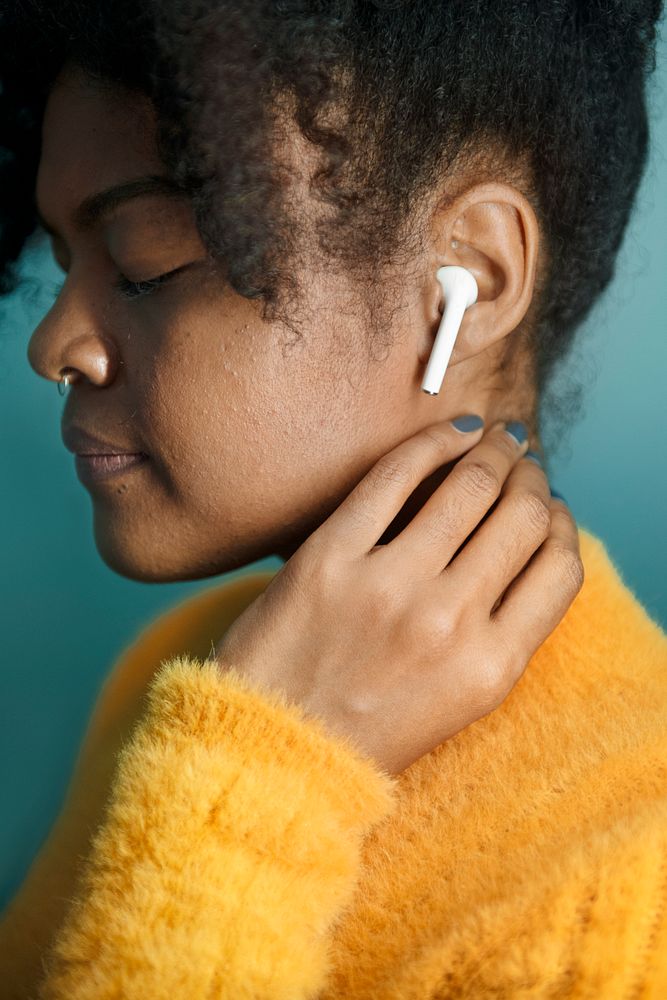 Woman enjoying music through wireless earphones digital device