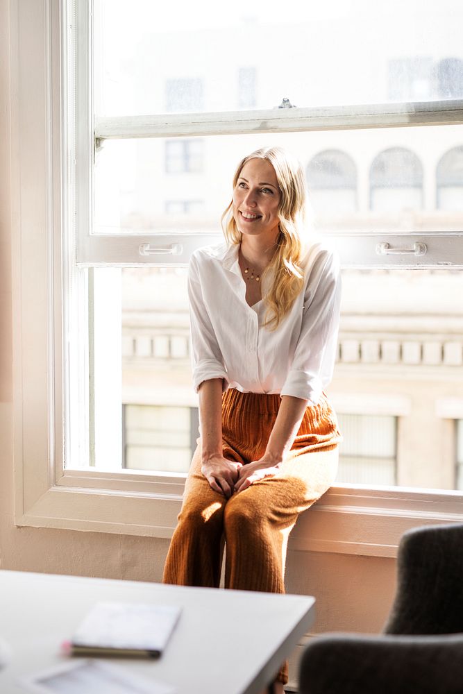 Happy woman sitting on a window sill