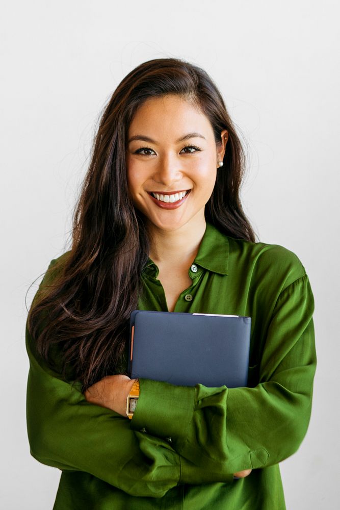 Cheerful woman in green shirt holding blue notebook
