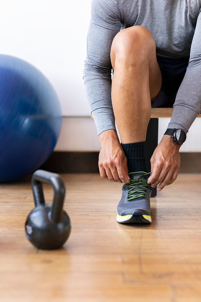 Sportsman tying his shoelaces in the gym