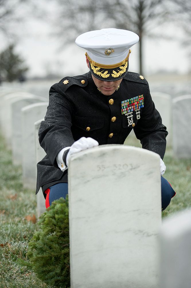 Marine Corps Major Carl Tucker touches the grave of Navy veteran and Dept. of Defense employee Robert Henry Bruette after…