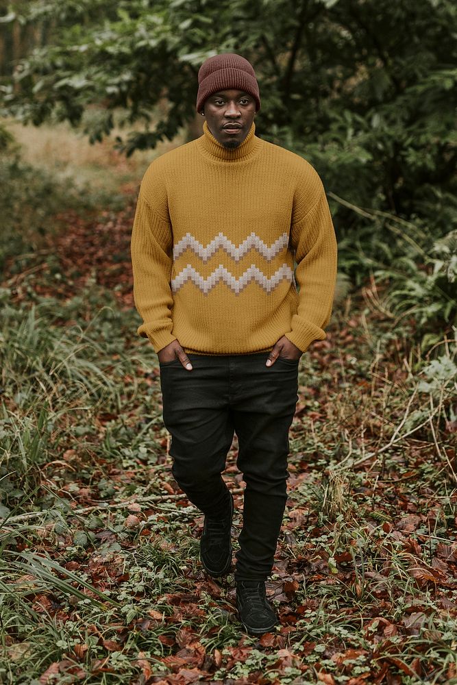 Man in mustard yellow turtleneck sweater walking in autumn forest
