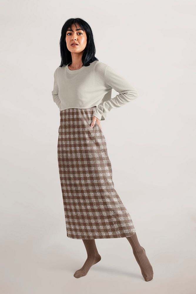Woman wearing beige cropped top over plaid brown dress, minimal autumn apparel fashion design