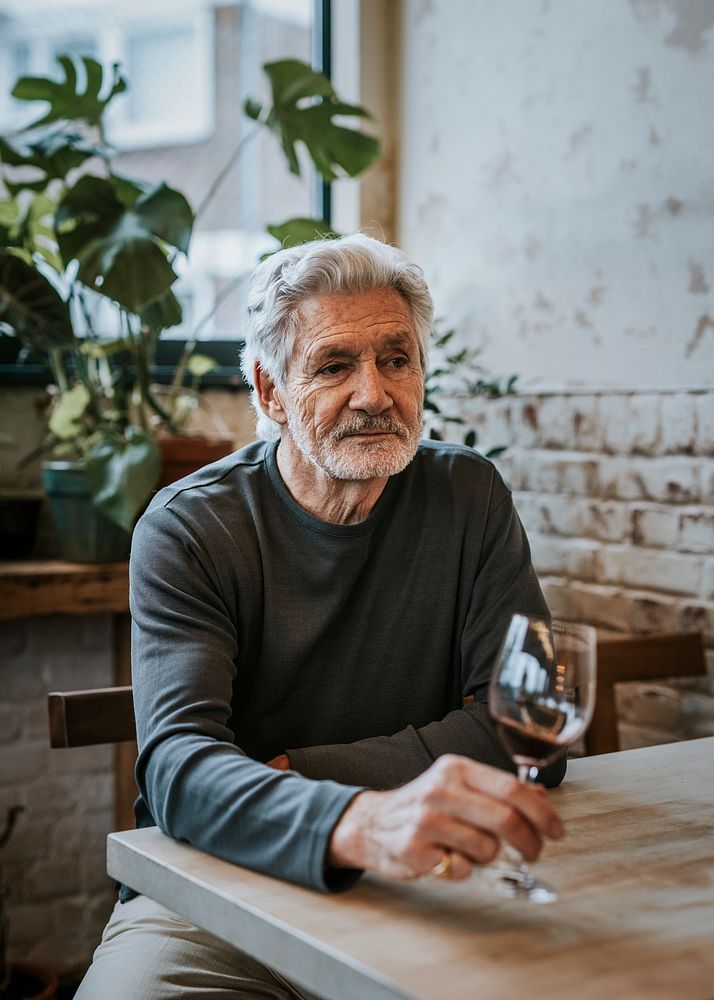 Retired man drinking wine alone at restaurant  