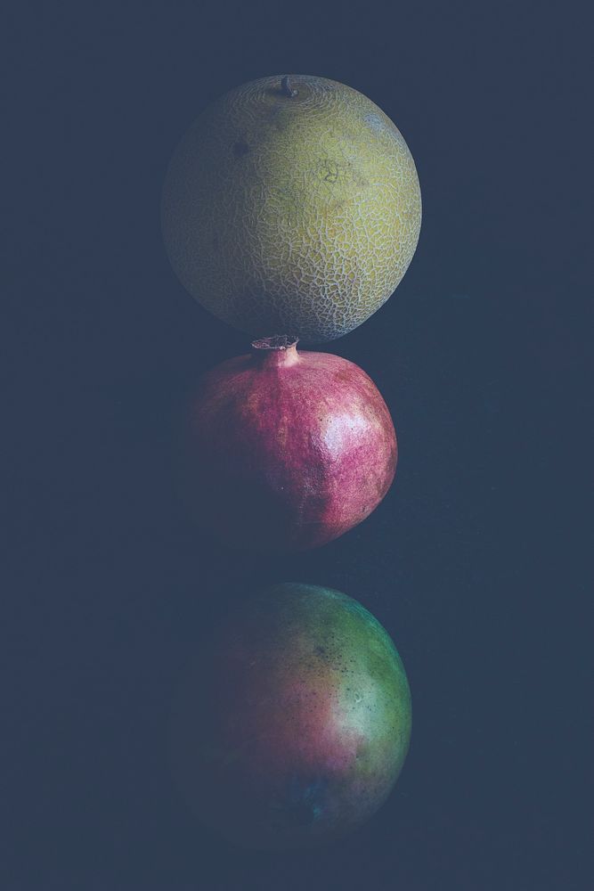 Three round fruits on dark background