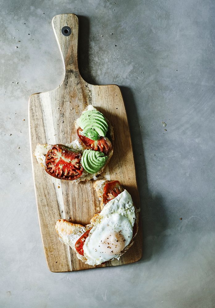 Croissant with tomatoes and avocado on a chopping board