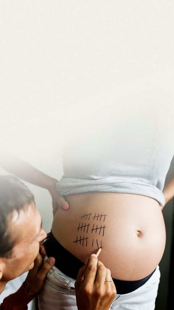 Father marking pregnancy due date on a woman&rsquo;s baby bump text space social story 