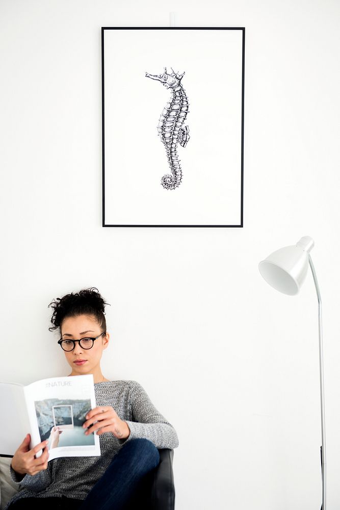 Woman relaxing with a photo frame mockup hanging on the wall