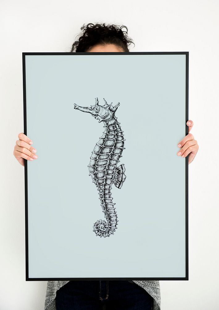 Woman holding hand drawing seahorse picture in photo frame