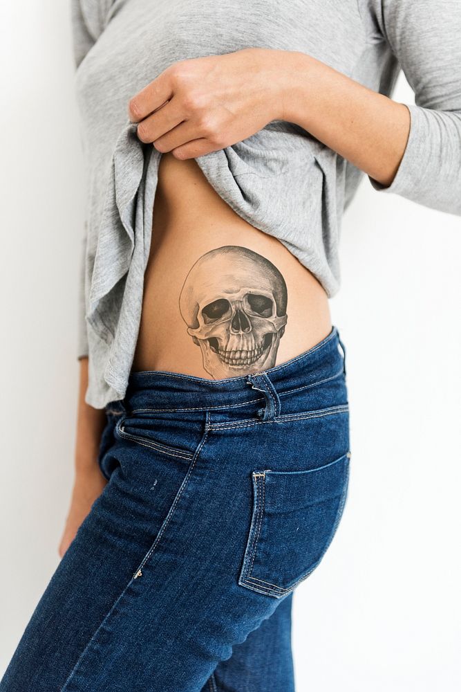 Woman showing a skull tattoo on her waist
