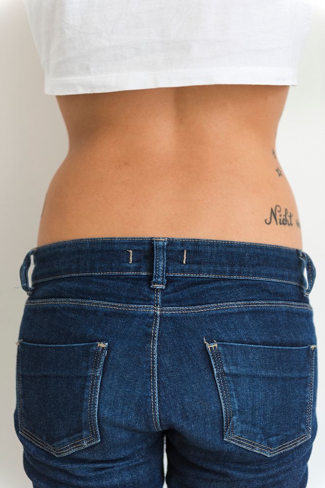 A woman is showing her tattoo on her hips