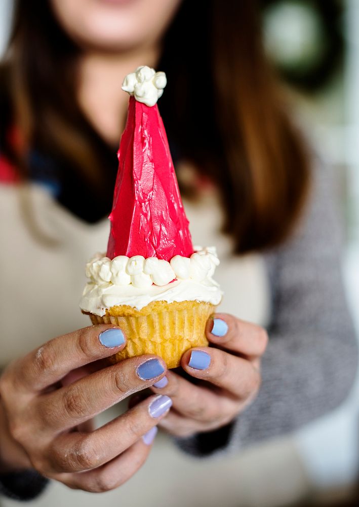 Woman holding up a Santa hat cupcake