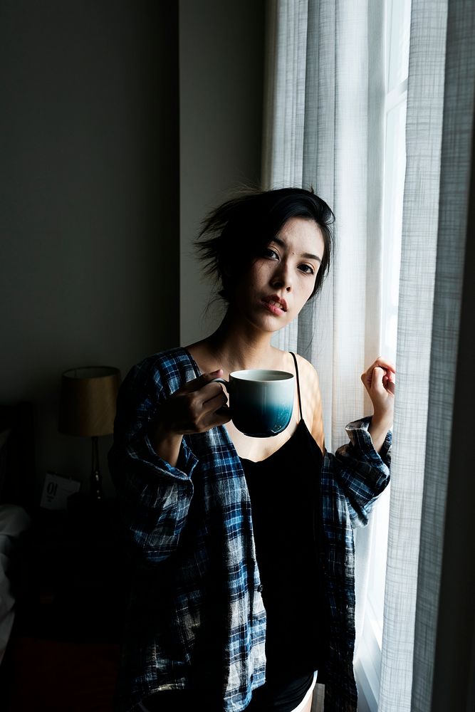 Girl drinking coffee by the window