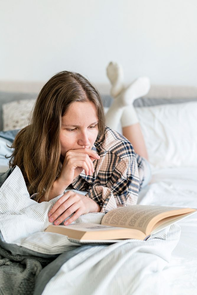 Caucasian woman reading book in bed