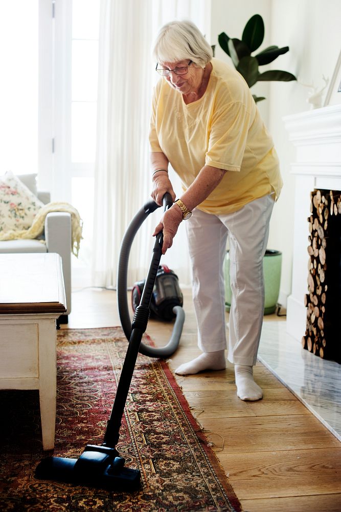 Senior woman vacuuming a carpet
