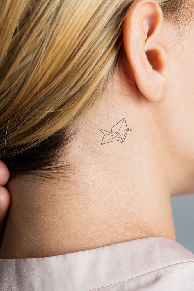 Closeup of a simple behind the ear tattoo of a young woman