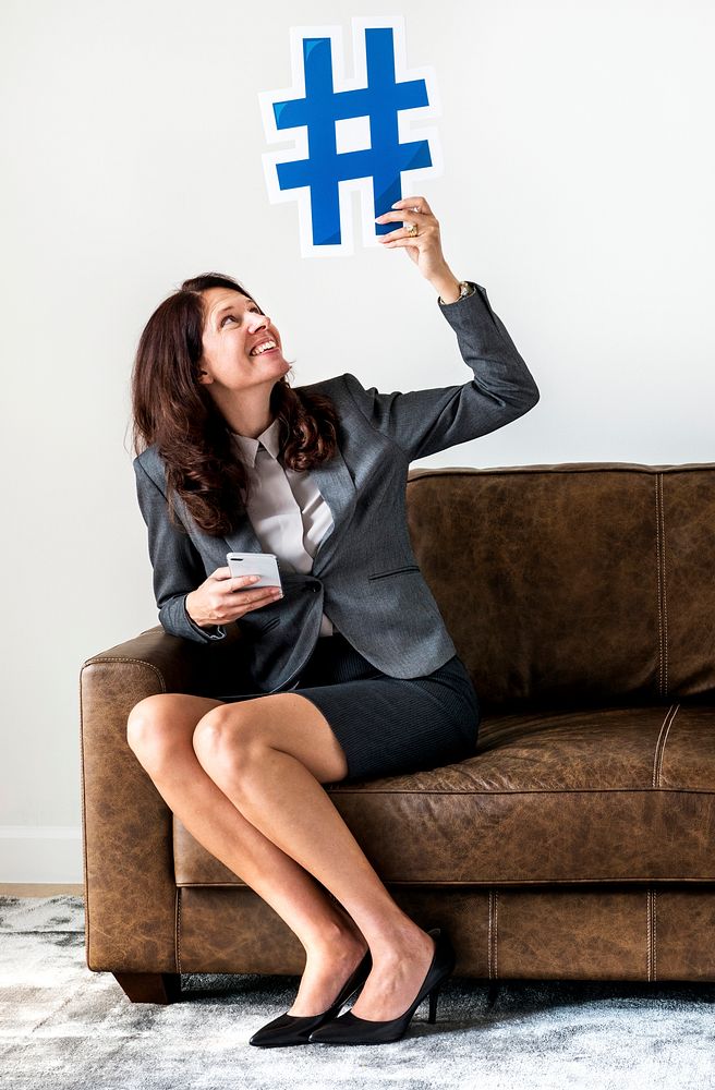 Businesswoman sitting on couch holding icon