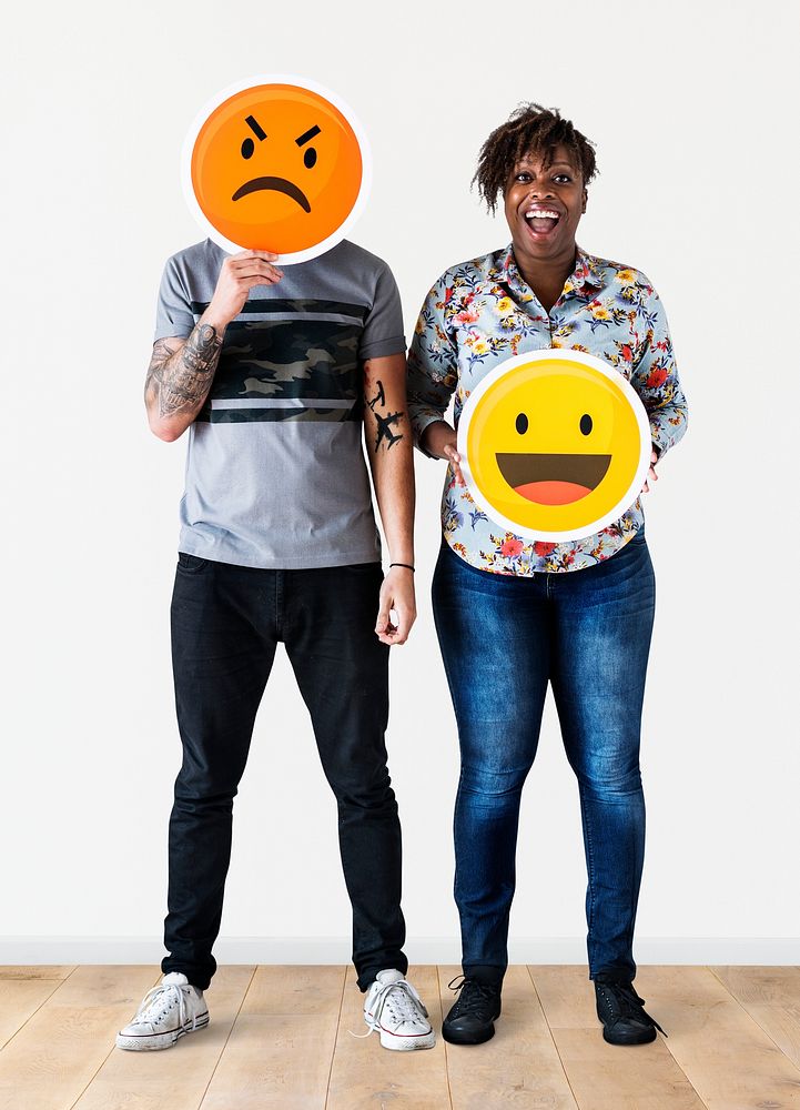 Interracial couple holding an expressive emoticon face facial expression frown and smile relationship issue concept