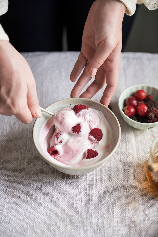 Woman mixing raspberries in a bowl of yogurt