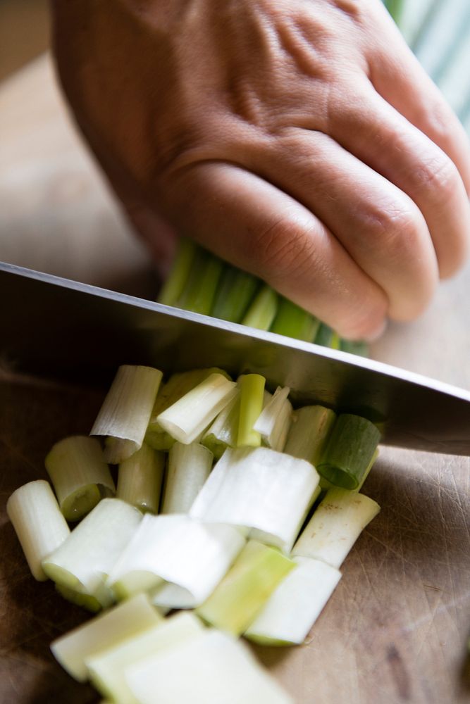 Woman chopping green onions on a cutting board