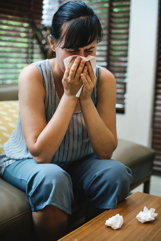 Sick woman sneezing into tissue