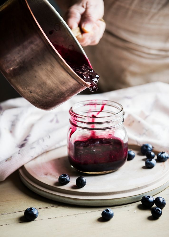 Hand pouring jam into a jar
