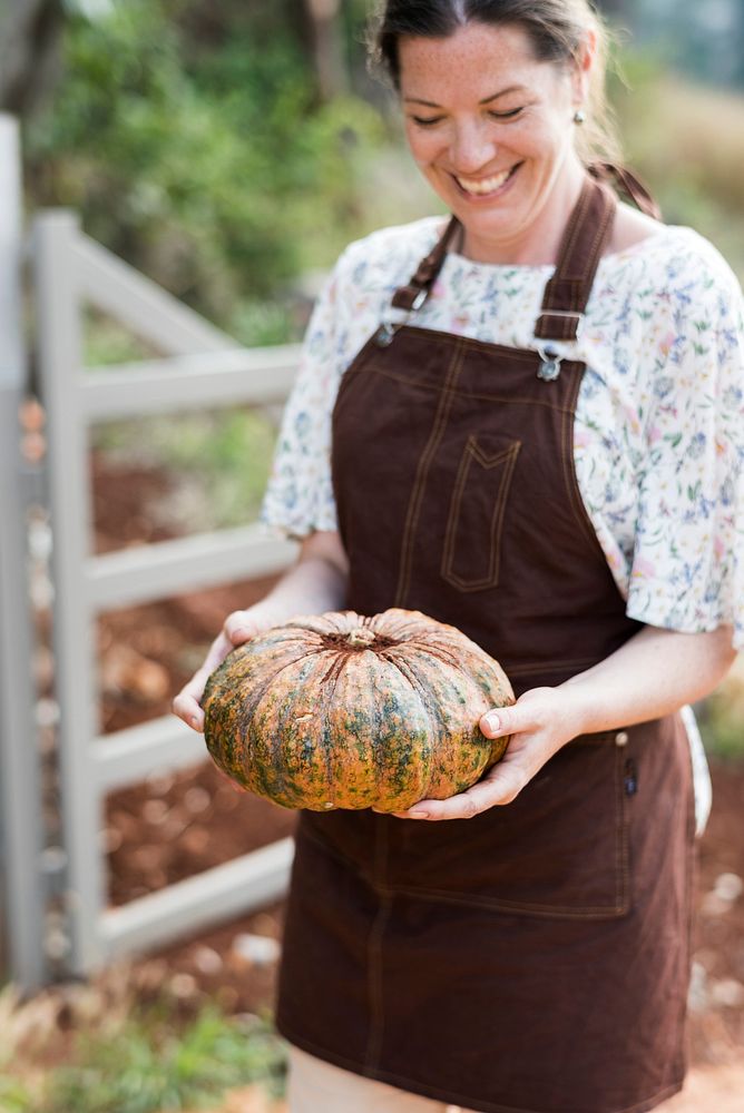 Female farmer holding a large pumpkin