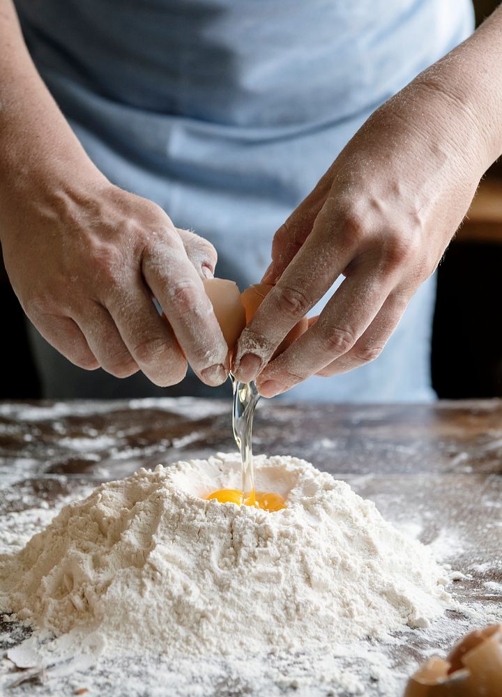 Baker cracking egg into flour