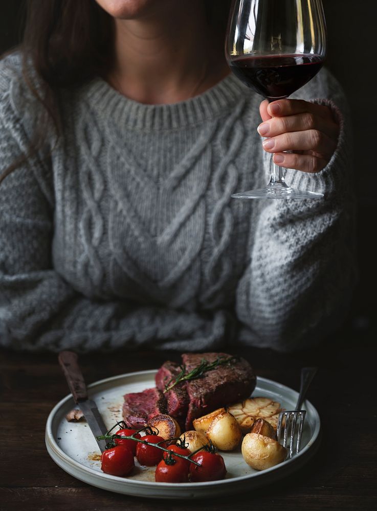 Woman drinking red wine with a steak