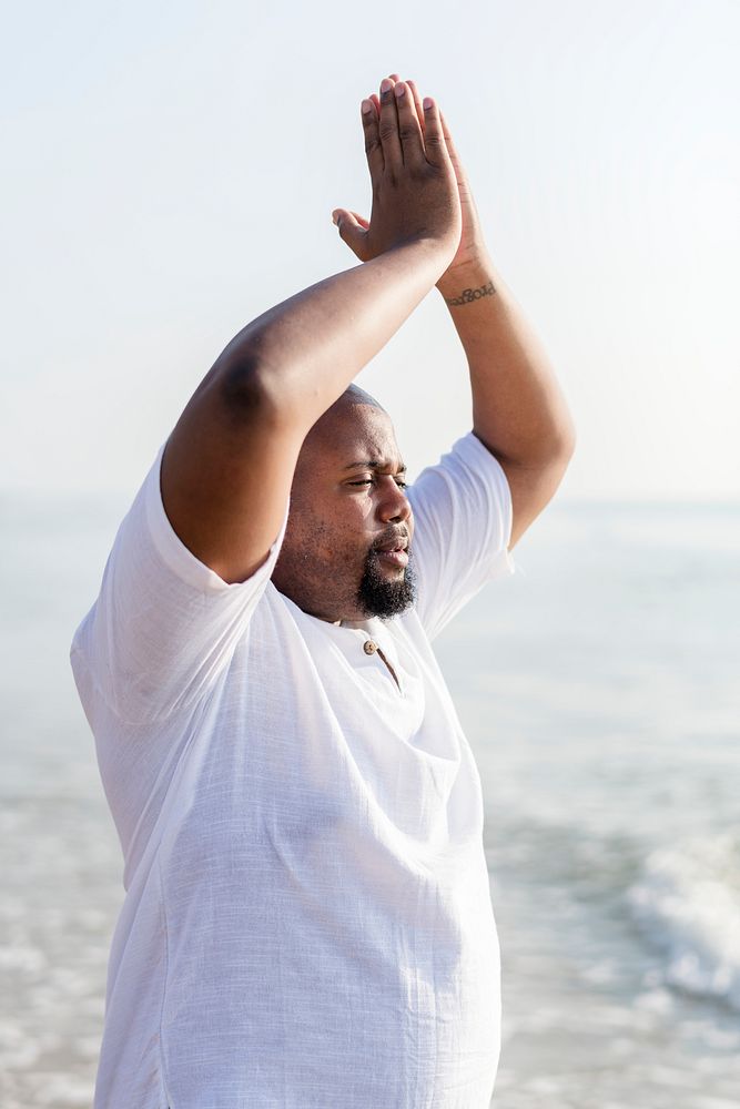 African American man practicing yoga at the beach