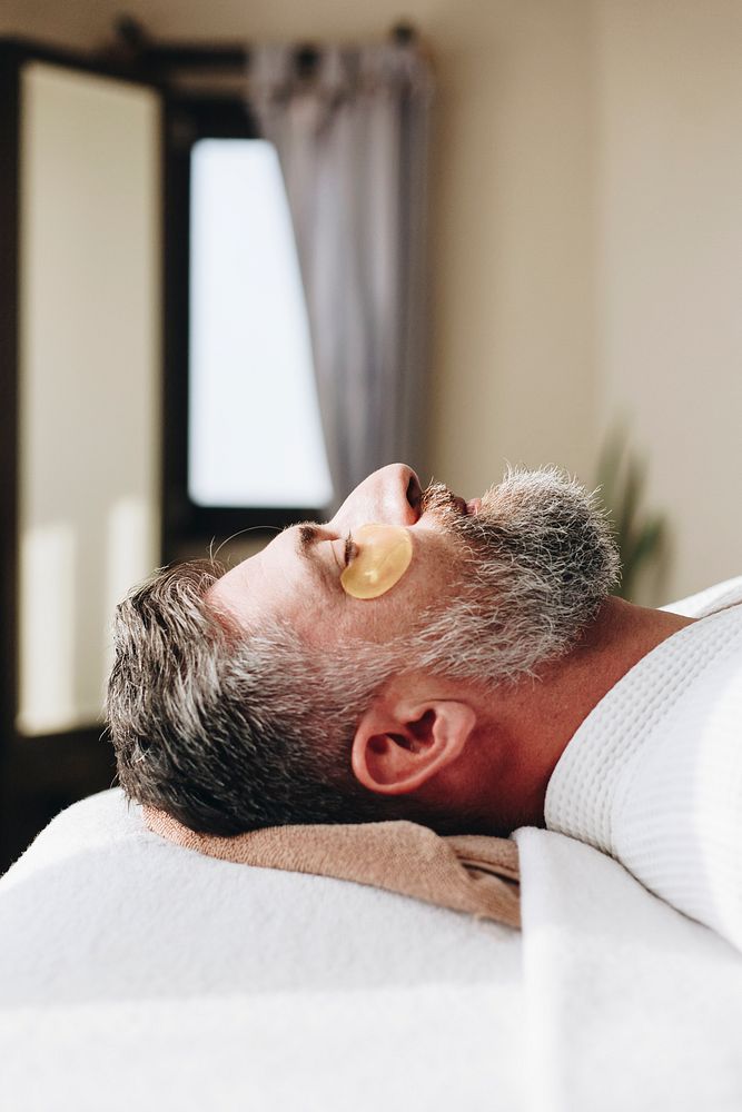 Man relaxing with a golden eye mask treatment