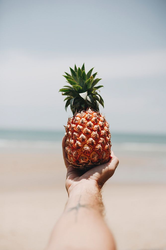 Man holding a pineapple at the beach