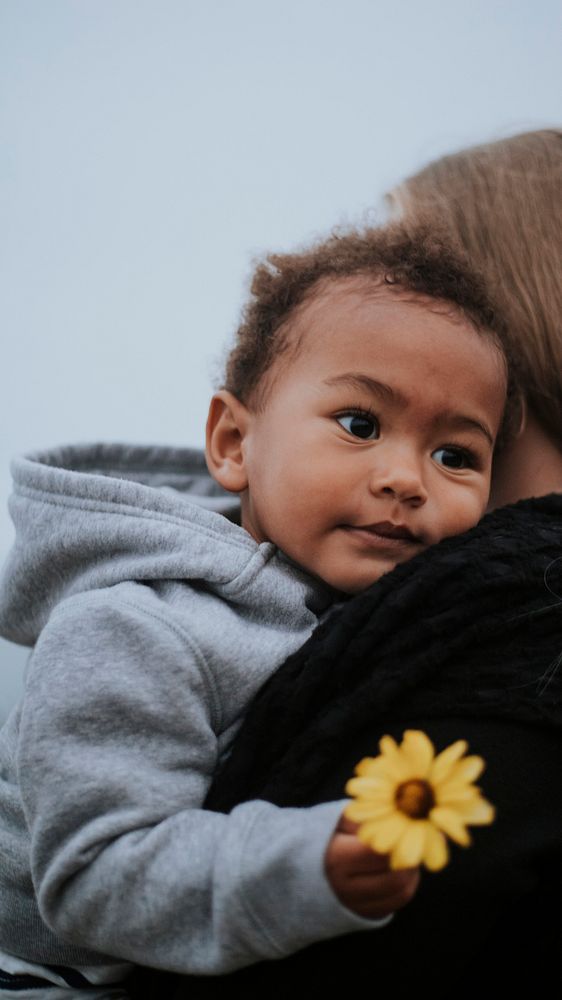 Young boy holding a flower while being carried by his mom mobile phone wallpaper