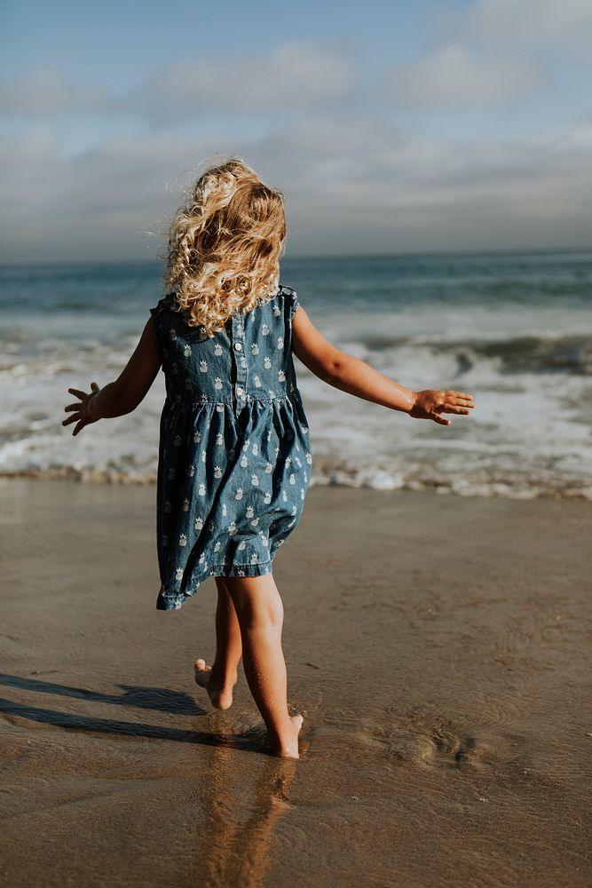 Little girl walking barefoot at the beach