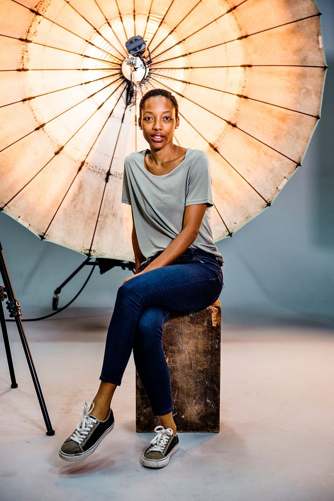 Photographer assistant posing in front of a reflective umbrella in a studio