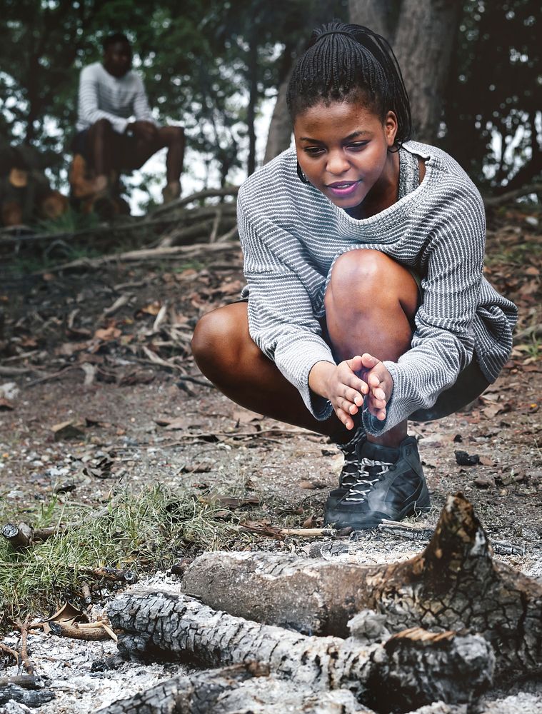 Woman warming her hands by the campfire ashes