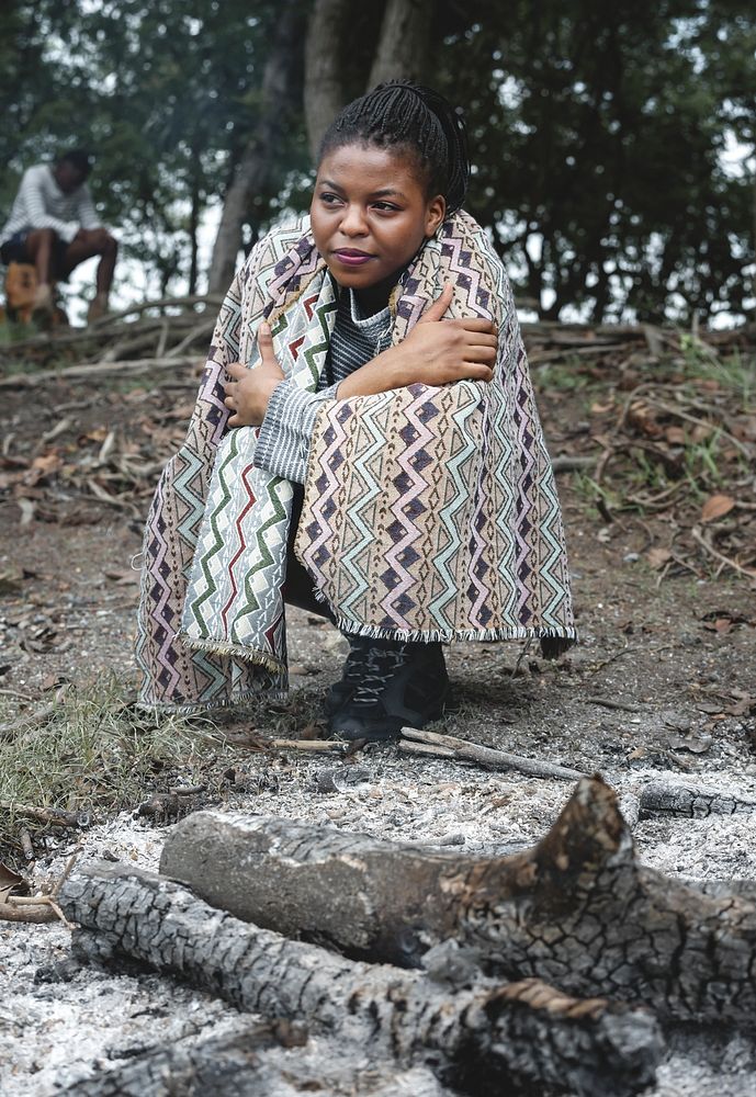 Woman sitting by a the bonfire ashes