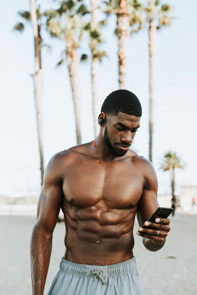 Fit man listening to music while at the beach
