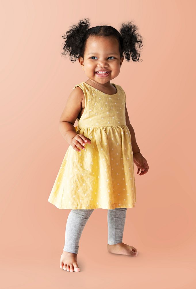 Happy little girl in a yellow dress standing