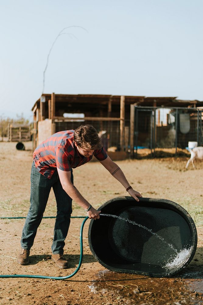 Farmer washing dirt off a black tub