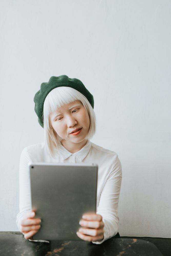 Albino girl with a green beret using her tablet