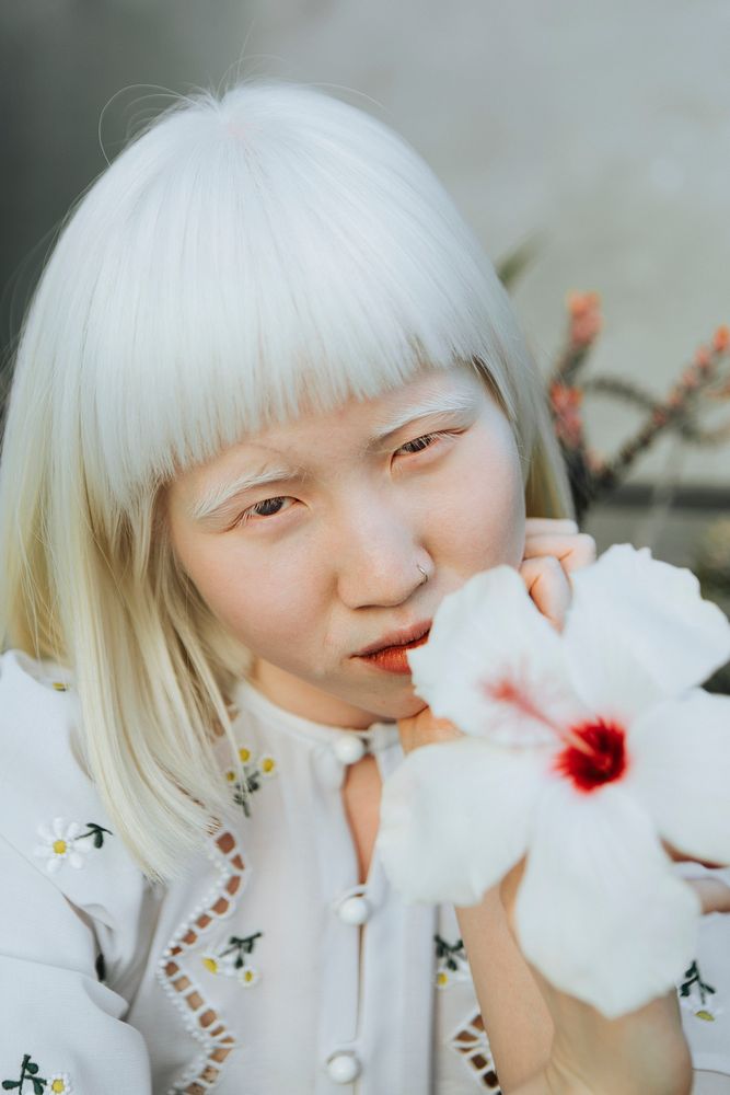 Portrait of an albino girl with a white hibiscus