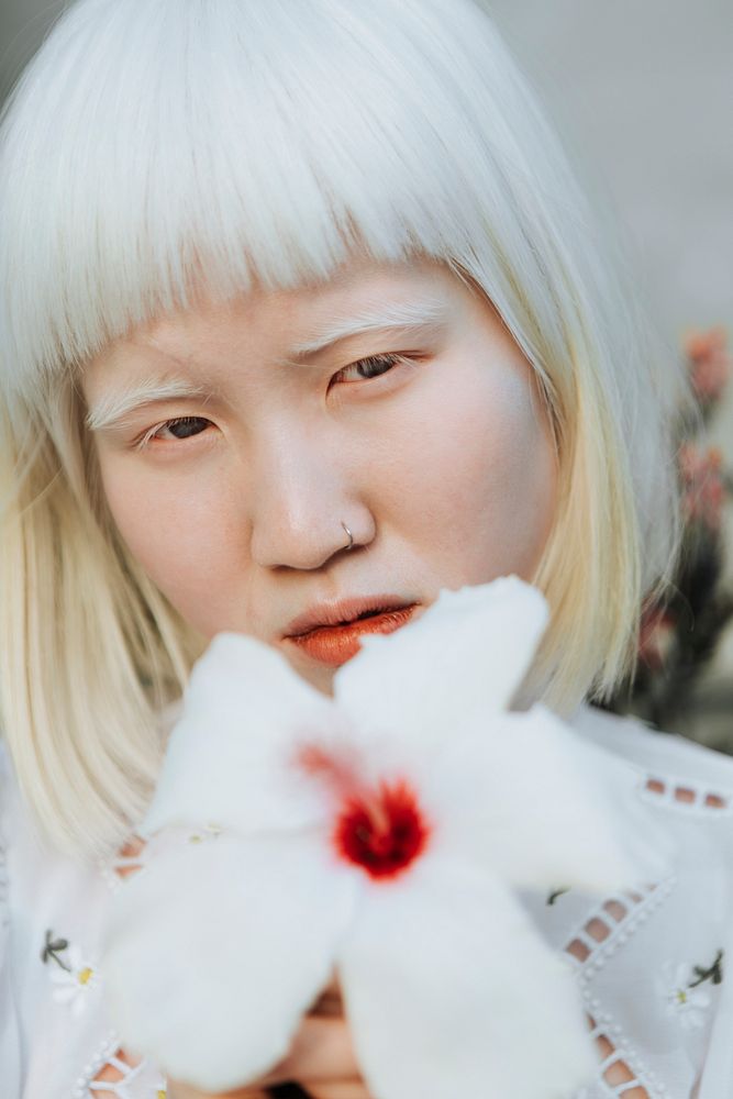 Portrait of an albino girl with a white hibiscus